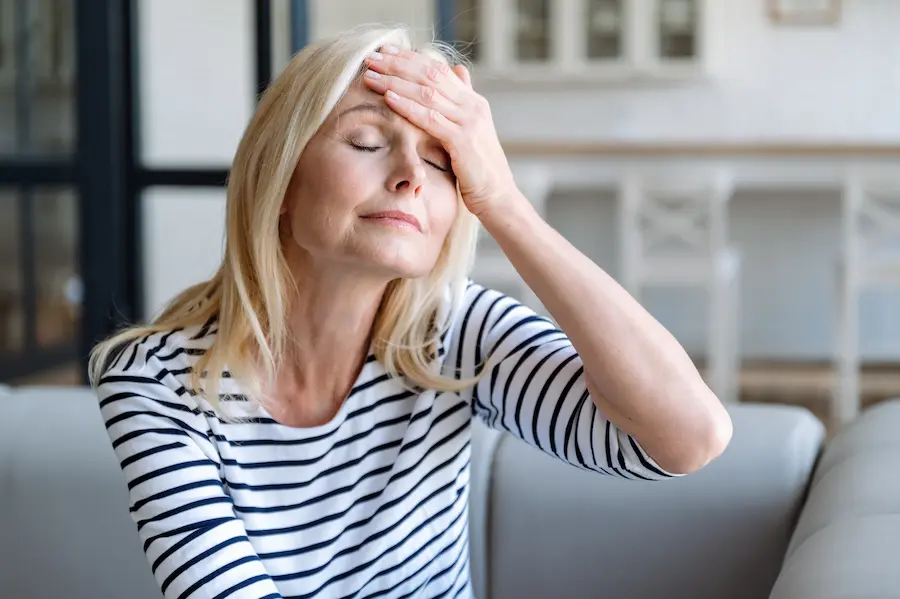 sick mature woman touching forehead suffering from headache - Ileria CPR Feedback training technology