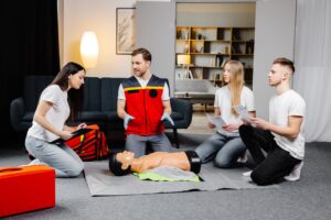 young man instructor helping make first aid heart compressions with dummy group training indoors 1 - Ileria CPR Feedback training technology