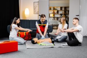 young man instructor helping make first aid heart compressions with dummy group training indoors 3 - Ileria CPR Feedback training technology